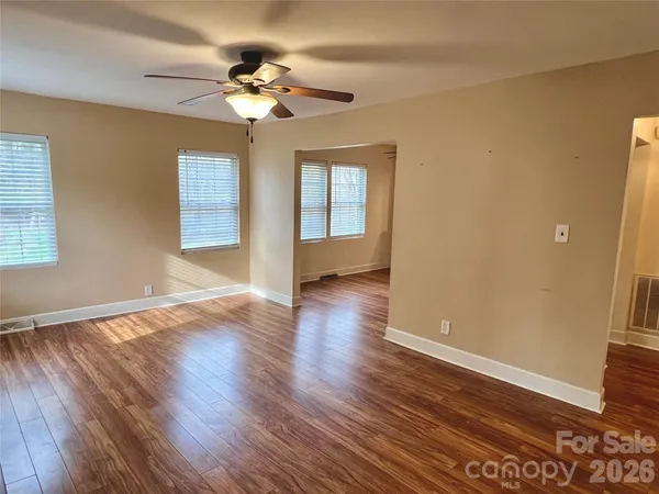 a view of an empty room with wooden floor and a window