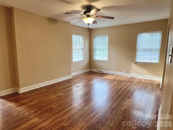 a view of an empty room with window and wooden floor