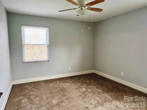 an empty room with a window and ceiling fan