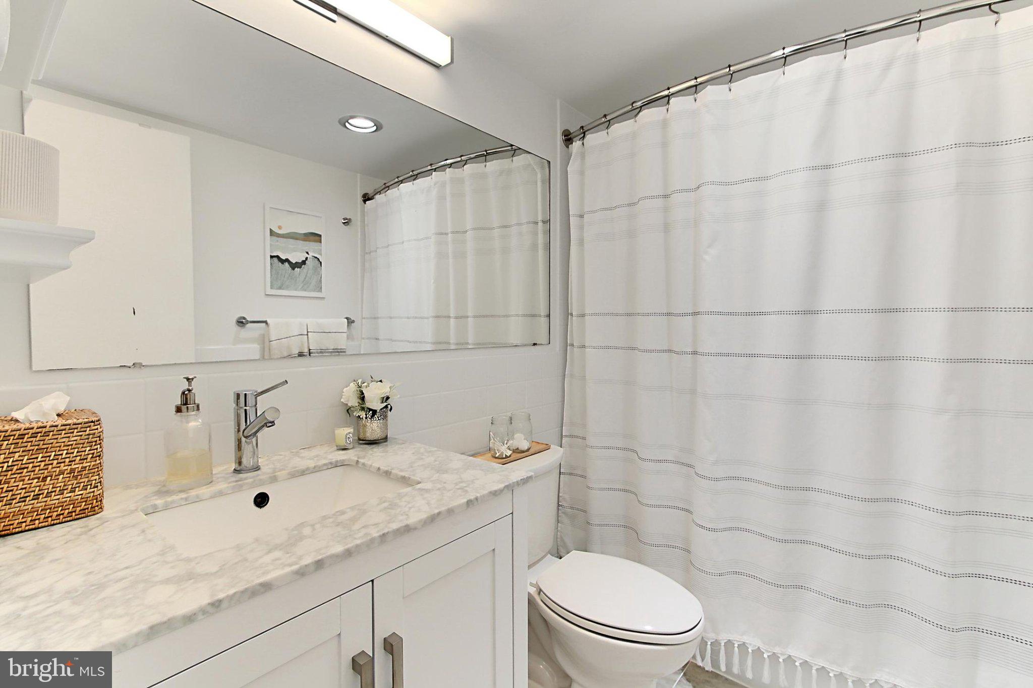 700 7th Street Southwest, Unit 730 Washington, DC 20024 - Photo 11 of 56 a bathroom with a granite countertop sink a toilet and a mirror