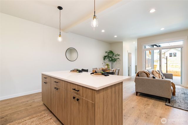 a living room with kitchen island a sink and a chandelier