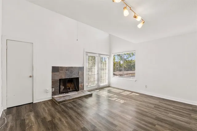 a view of an empty room with wooden floor fireplace and a window