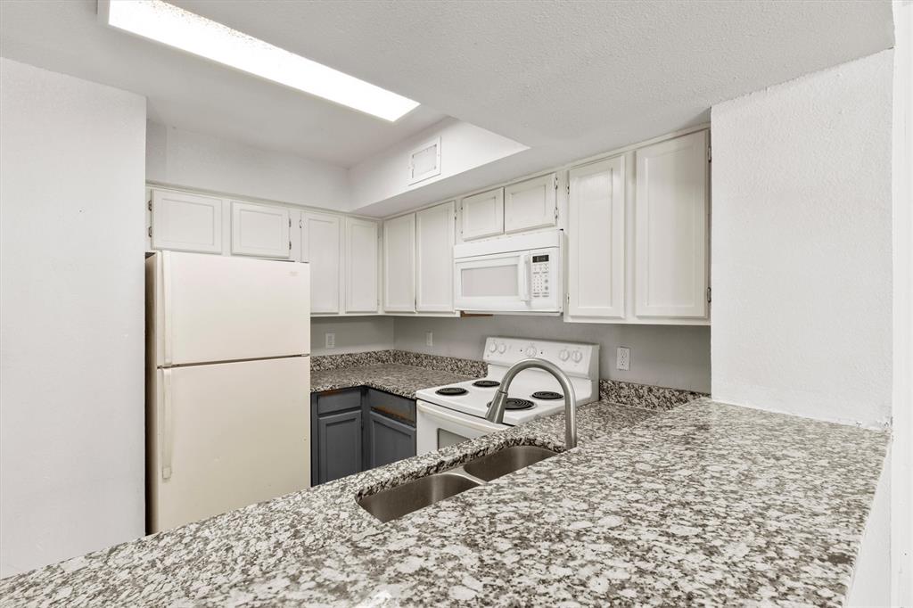 9807 Walnut Street, Unit 202 Dallas, TX 75243 - Photo 6 of 16 a kitchen with a refrigerator a stove and white cabinets