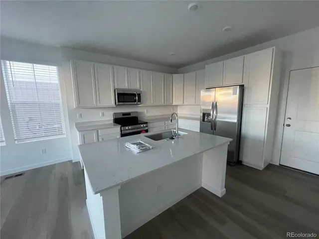 a kitchen with granite countertop white cabinets and stainless steel appliances