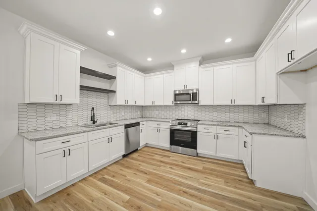 a large kitchen with granite countertop a stove top oven a sink a counter space and cabinets