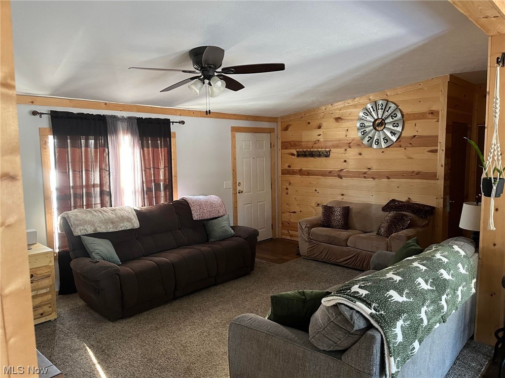 37604 Eagleton Road Lisbon, OH 44432 - Photo 10 of 50 Living room featuring wooden walls, dark carpet, and ceiling fan
