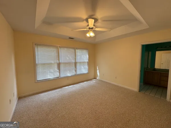an empty room with chandelier fan and windows