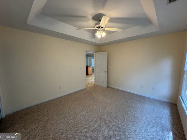 an empty room with a chandelier fan and windows