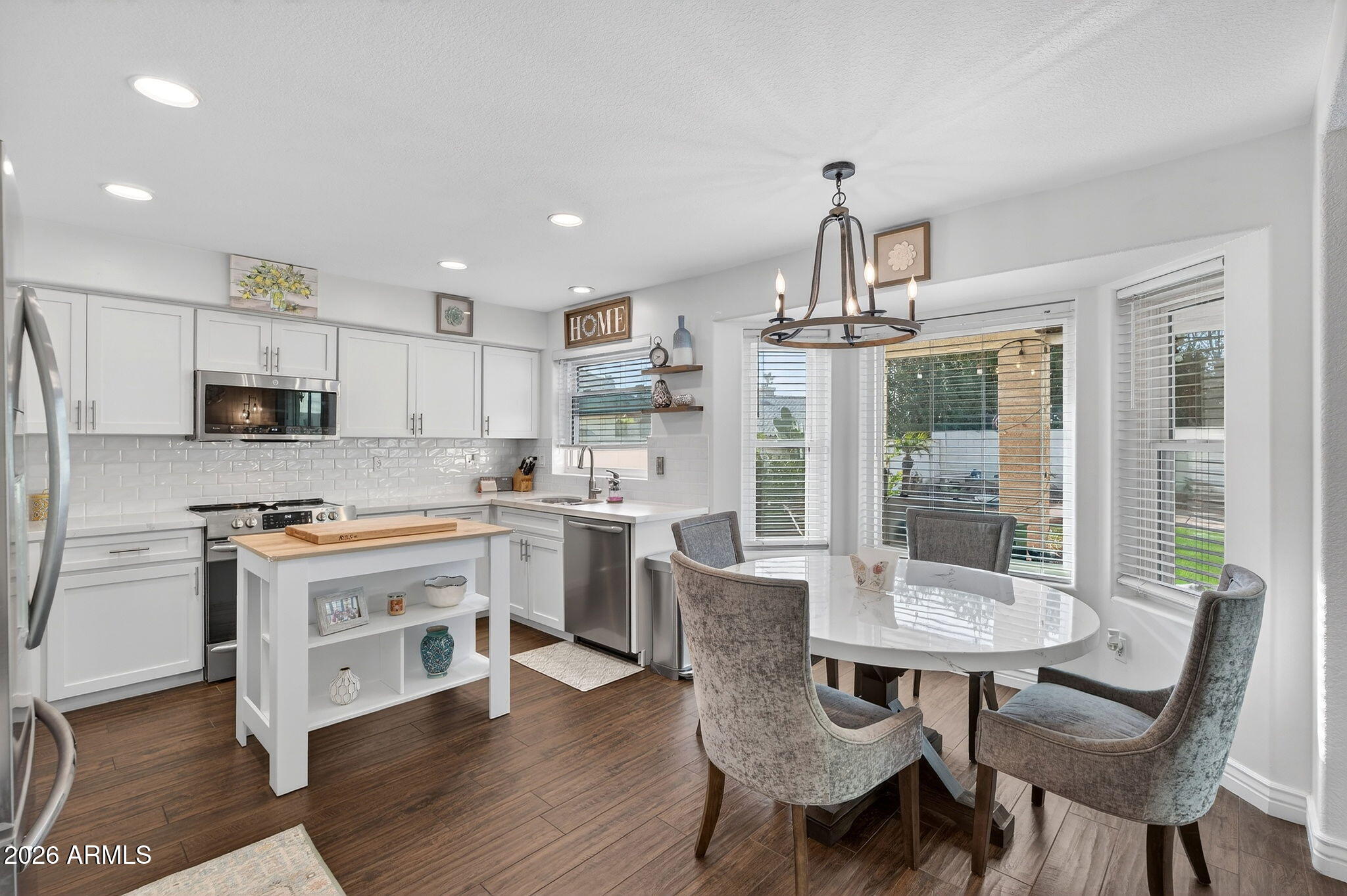 3615 East Desert Willow Road Phoenix, AZ 85044 - Photo 15 of 65 a open kitchen with stainless steel appliances a dining table chairs and white cabinets