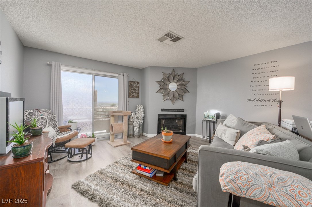 2240 Highpointe Drive, Unit 203 Laughlin, NV 89029 - Photo 13 of 38 Living room featuring a textured ceiling, a fireplace, wood finished floors, and visible vents