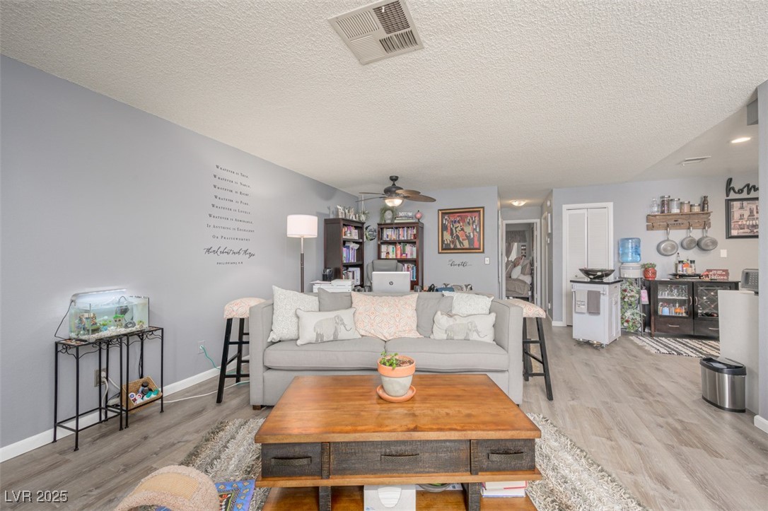 2240 Highpointe Drive, Unit 203 Laughlin, NV 89029 - Photo 14 of 38 Living room featuring a textured ceiling, ceiling fan, visible vents, and light wood finished floors