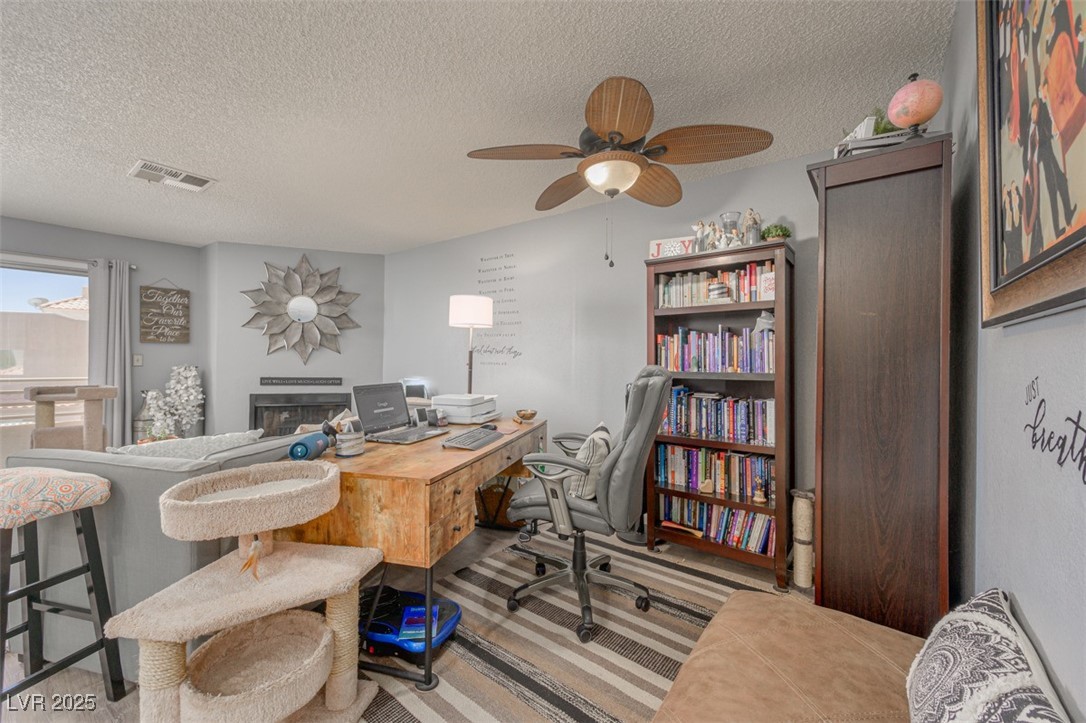 2240 Highpointe Drive, Unit 203 Laughlin, NV 89029 - Photo 15 of 38 Office area with ceiling fan, a textured ceiling, visible vents, a fireplace, and carpet