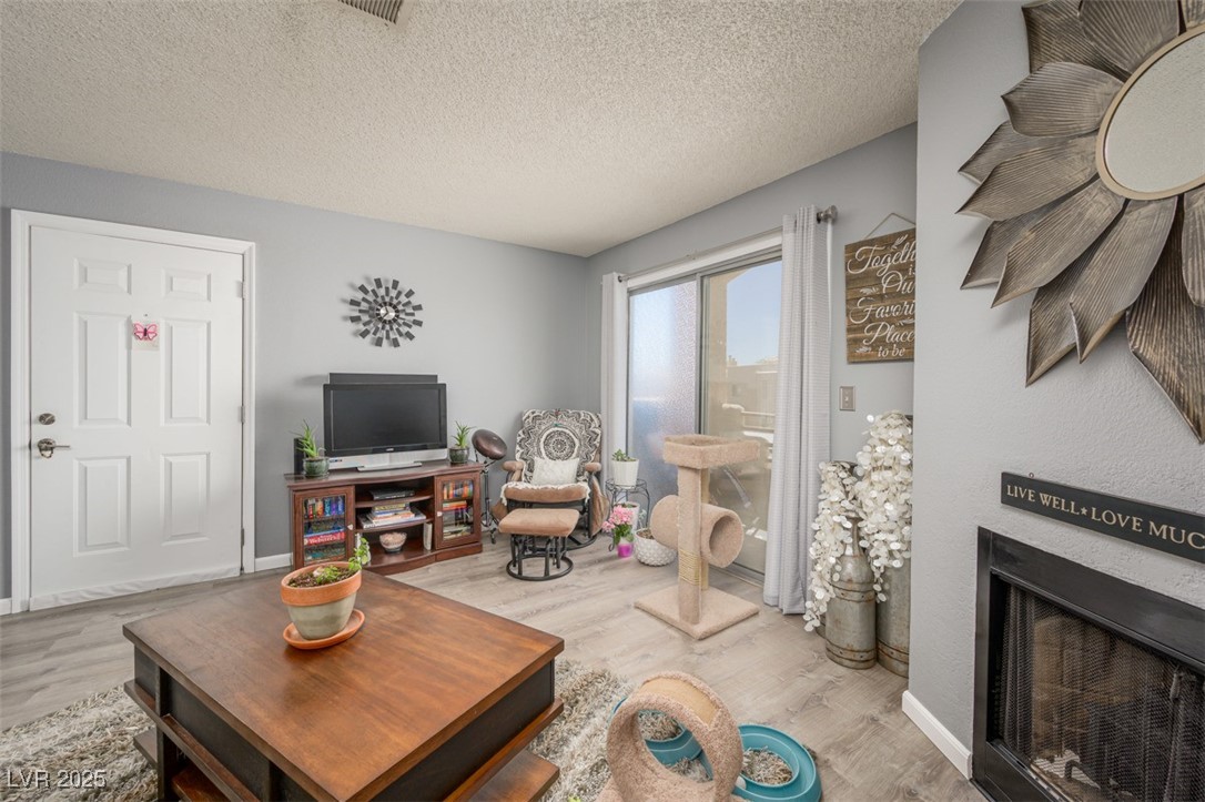 2240 Highpointe Drive, Unit 203 Laughlin, NV 89029 - Photo 16 of 38 Living area featuring a textured ceiling, a fireplace, and wood finished floors