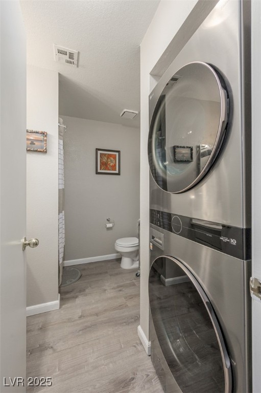 2240 Highpointe Drive, Unit 203 Laughlin, NV 89029 - Photo 27 of 38 Clothes washing area with laundry area, visible vents, wood finished floors, stacked washing maching and dryer, and baseboards