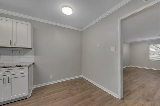 a view of an empty room with wooden floor and cabinets