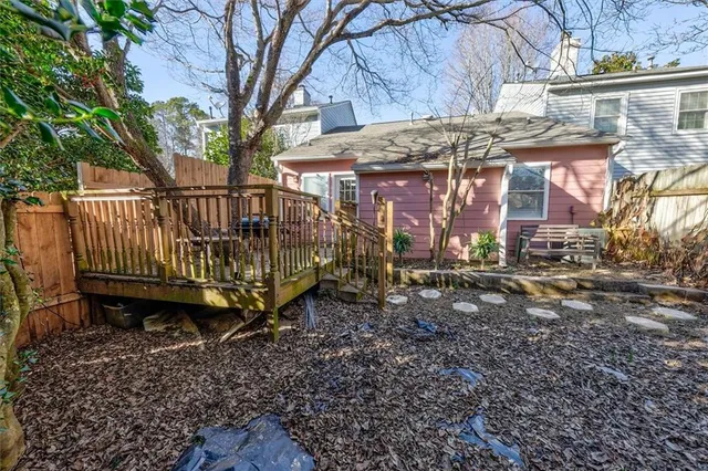 a view of a small house with a small yard and wooden fence