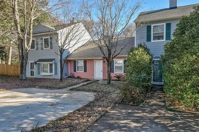 a view of a brick house next to a yard with large trees