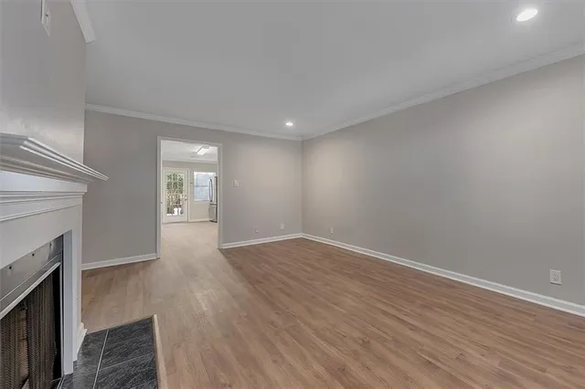 a view of an empty room with wooden floor and a fireplace