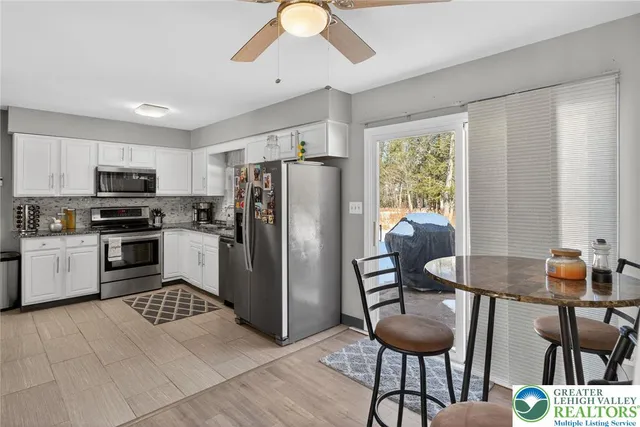 a kitchen with stainless steel appliances a refrigerator a stove a sink a dining table and chairs with wooden floor