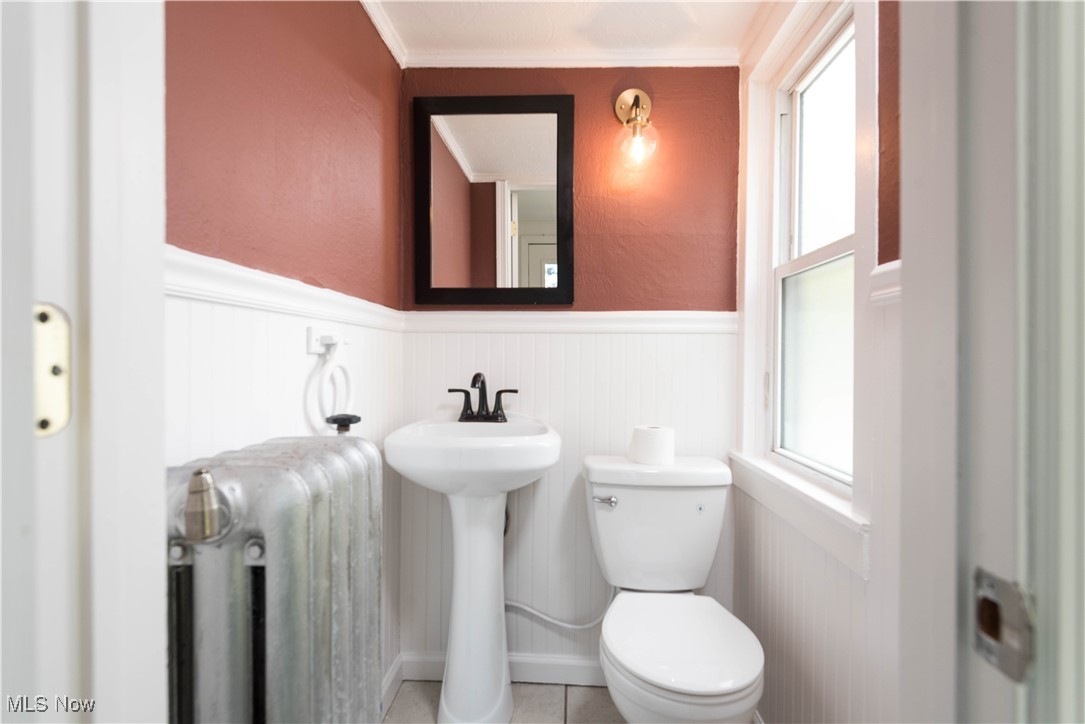 7003 Brecksville Road Independence, OH 44131 - Photo 20 of 35 Half bathroom featuring wainscoting, healthy amount of natural light, radiator, ornamental molding, and tile patterned floors