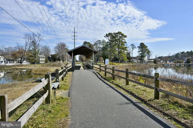 a view of a lake with a bench and trees in the background