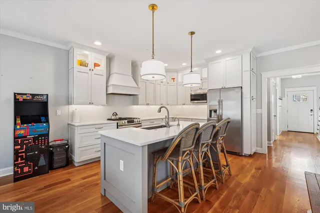 a kitchen with stainless steel appliances a stove a sink a center island and a wooden floor