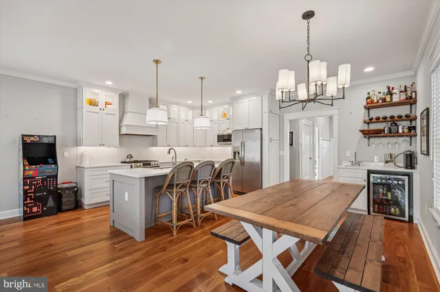 a open kitchen with stainless steel appliances granite countertop a stove a refrigerator a kitchen island a dining table and chairs with wooden floor