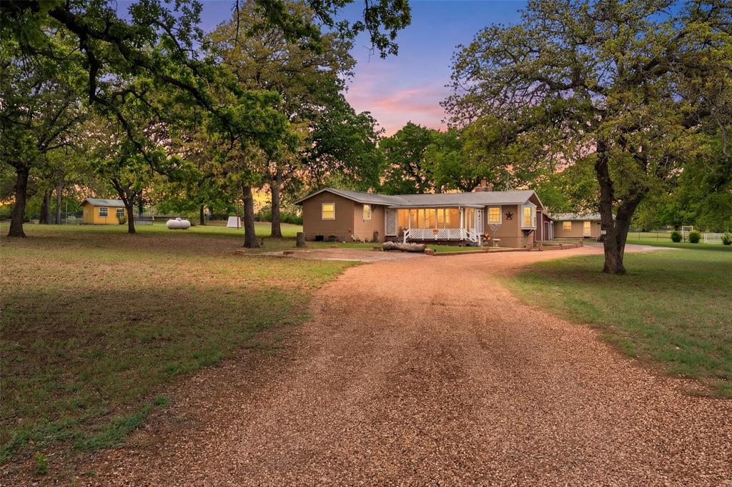 a view of a house with large trees and a yard