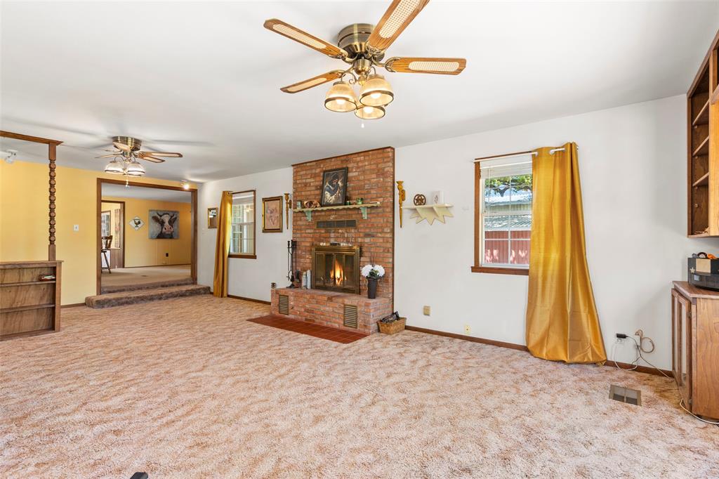 1500 County Road 404 Comanche, TX 76442 - Photo 11 of 39 Unfurnished living room with a ceiling fan, light carpet, and a fireplace