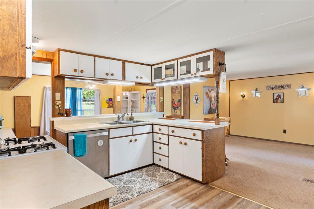 1500 County Road 404 Comanche, TX 76442 - Photo 12 of 39 a kitchen with stainless steel appliances a stove a sink and white cabinets with wooden floor