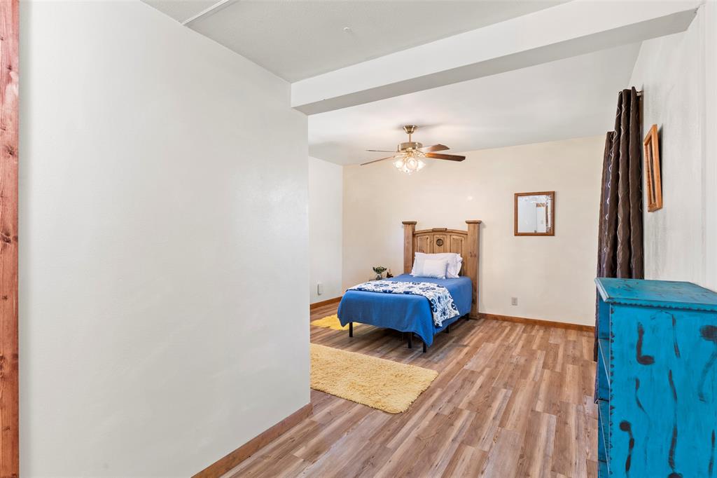 1500 County Road 404 Comanche, TX 76442 - Photo 18 of 39 a bedroom with a bed and wooden floor