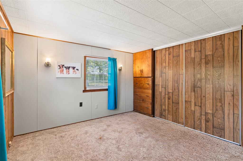 1500 County Road 404 Comanche, TX 76442 - Photo 20 of 39 Unfurnished bedroom with carpet flooring and wooden walls