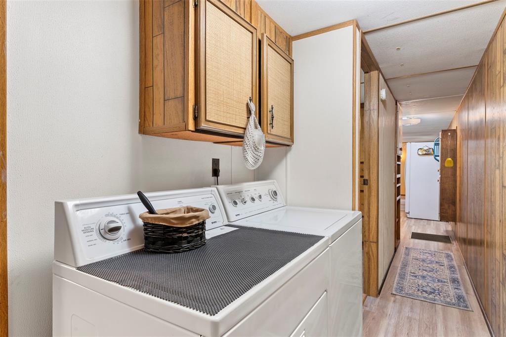 1500 County Road 404 Comanche, TX 76442 - Photo 23 of 39 Laundry area featuring light wood-style flooring, cabinet space, washer and clothes dryer, and wood walls