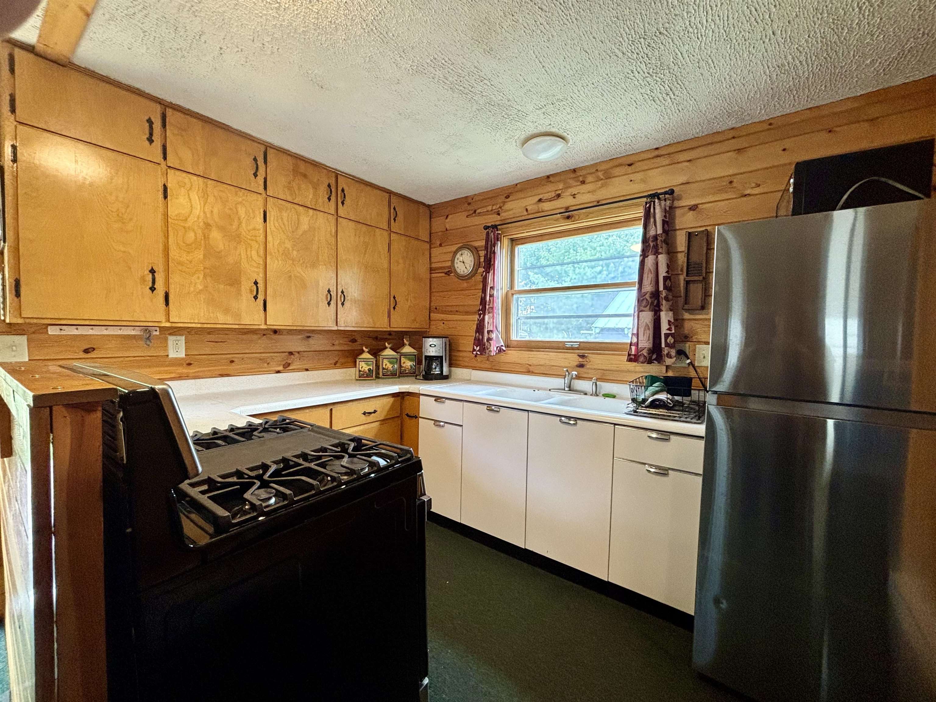 9724 State Highway 1 Isabella, MN 55607 - Photo 6 of 21 Kitchen with freestanding refrigerator, black gas stove, a sink, a textured ceiling, and wood walls
