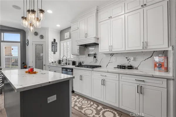 a kitchen with stainless steel appliances granite countertop a sink dishwasher and white cabinets with wooden floor