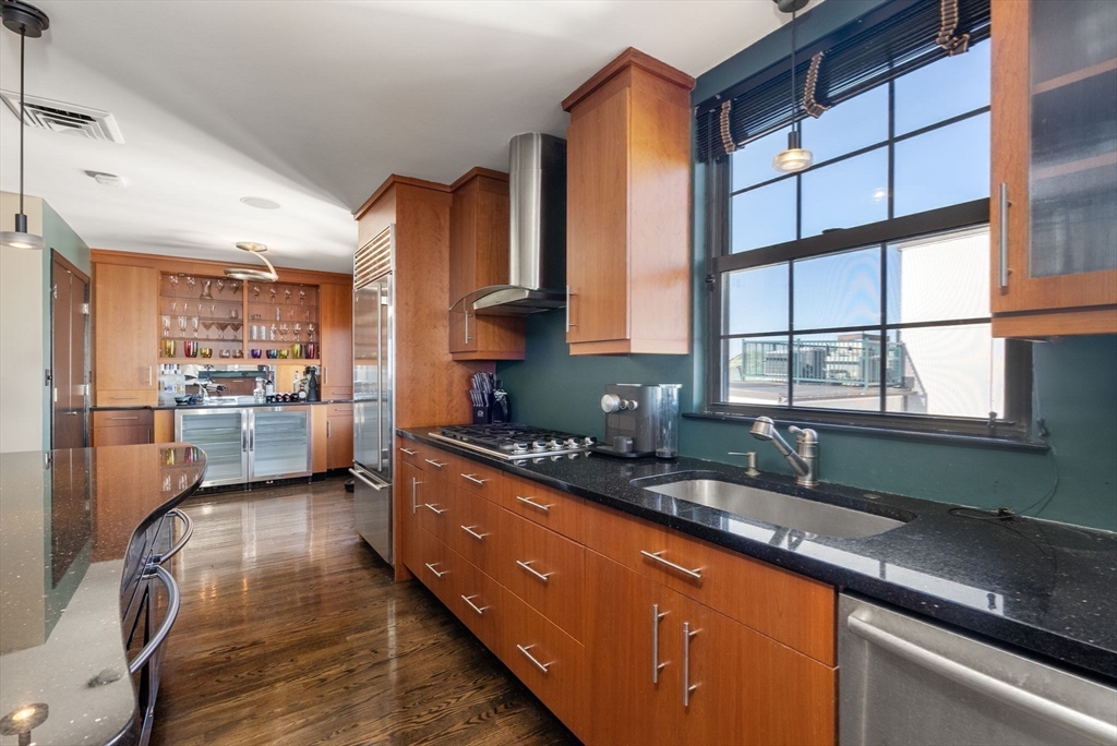 227 Summit Avenue, Unit E401 Brookline, MA 02446 - Photo 12 of 38 a kitchen with stainless steel appliances granite countertop a sink a stove and a wooden cabinets