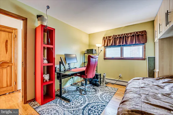 a bedroom with a bed and a dresser with wooden floor