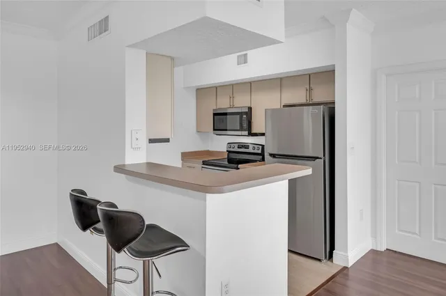 a kitchen with a refrigerator a stove a microwave and dining table with wooden floor