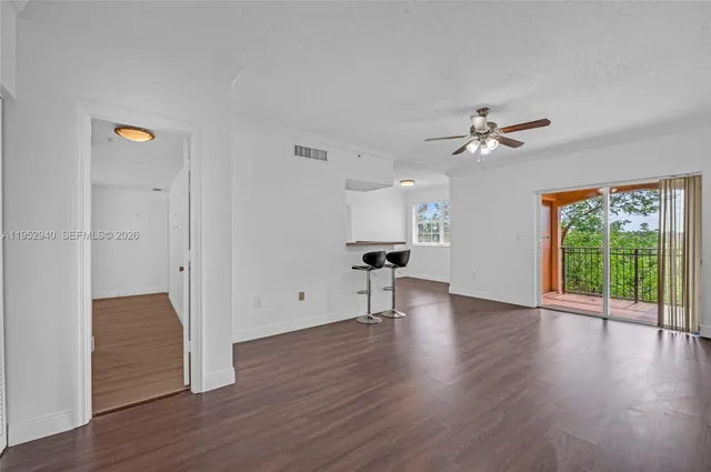 a view of an empty room with a window and wooden floor