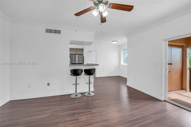 a view of empty room with wooden floor and fan