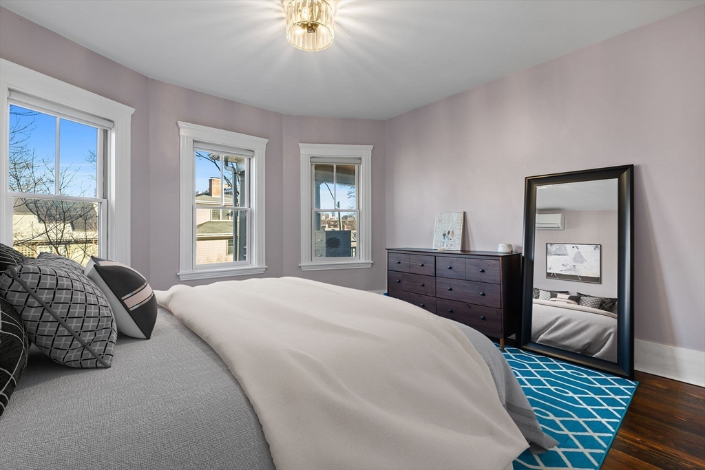 62 Atherton Road, Unit 1 Brookline, MA 02446 - Photo 20 of 24 a spacious bedroom with a bed and dresser with mirror