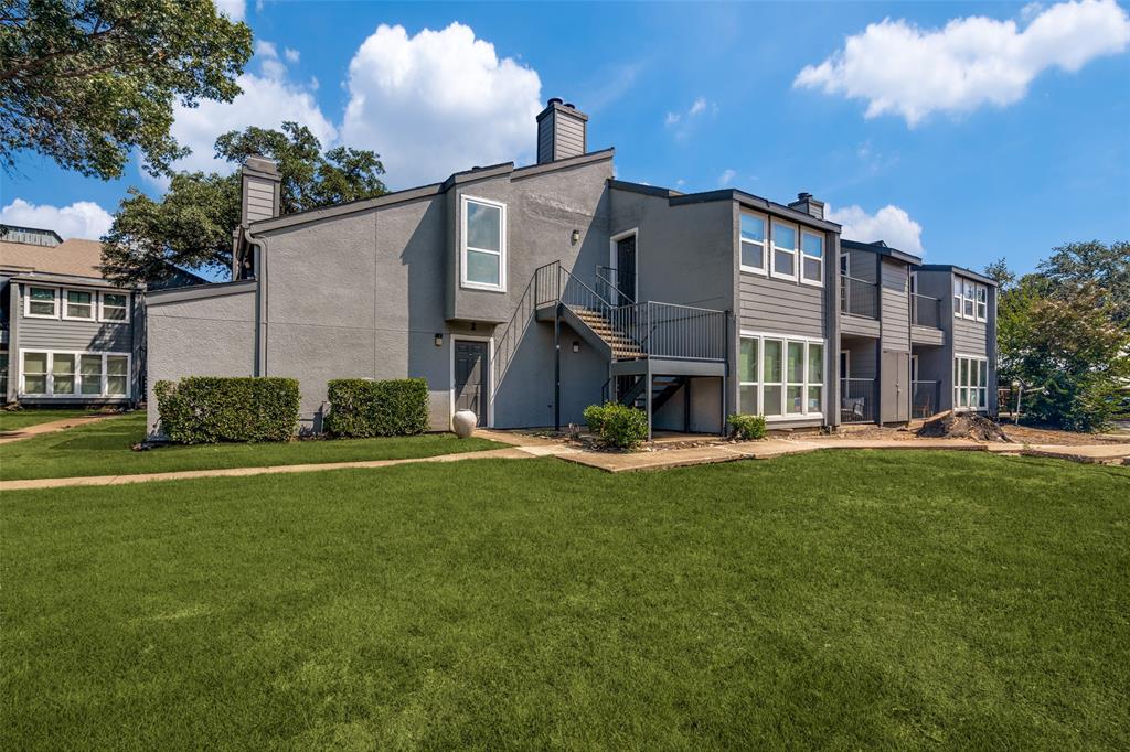 9696 Walnut Street, Unit 1216 Dallas, TX 75243 - Photo 5 of 19 The property features a grey exterior, multiple windows, and exterior staircases, set against a green lawn