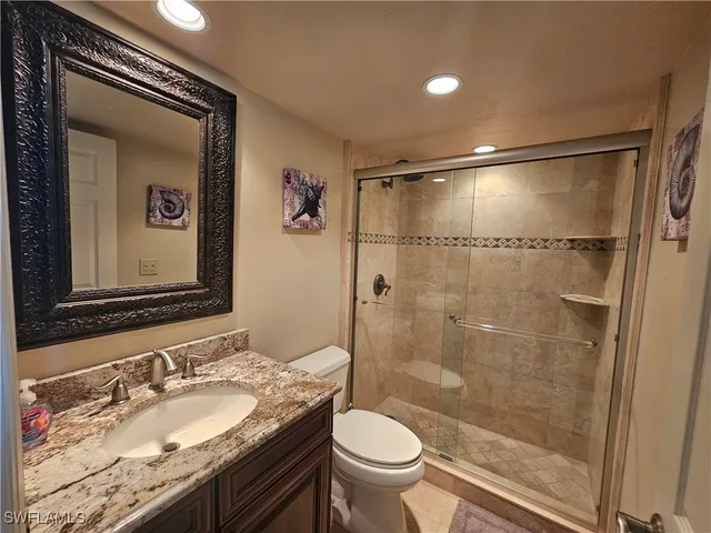 a bathroom with a granite countertop sink toilet mirror and shower