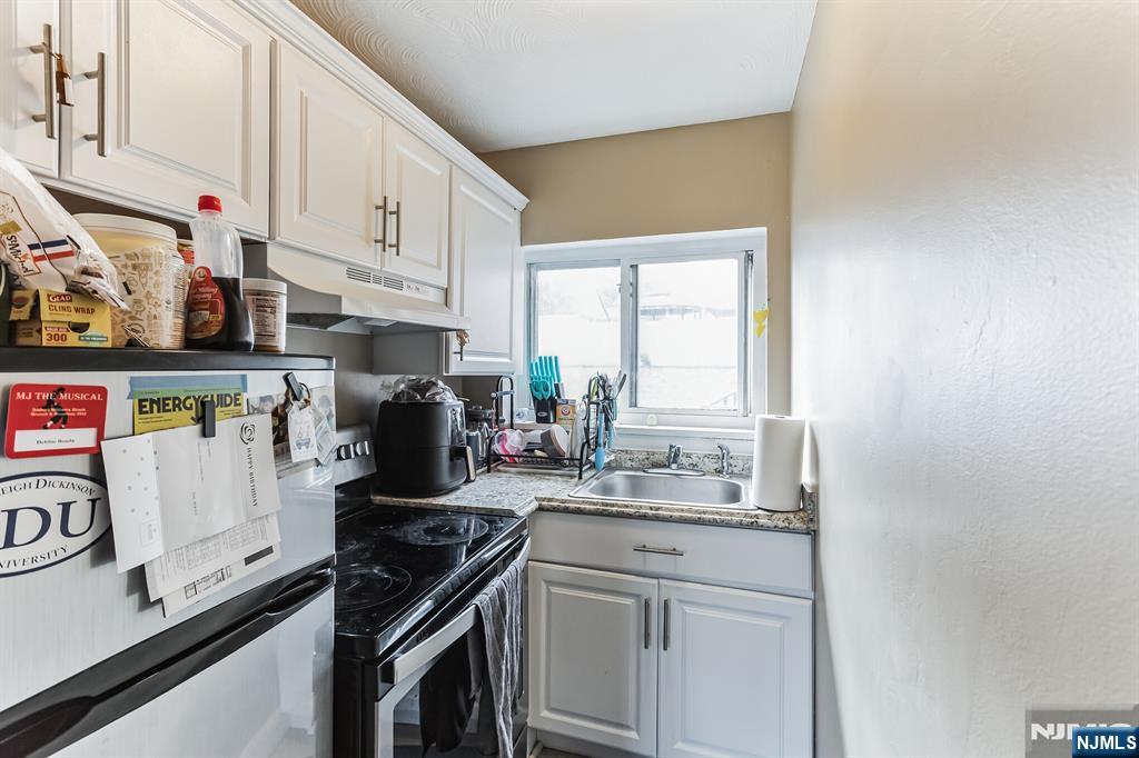 207 Polifly Road, Unit 2074 Hackensack, NJ 07601 - Photo 6 of 15 a kitchen with white cabinets and appliances