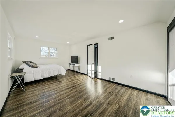 a spacious bedroom with a bed and a wooden floor