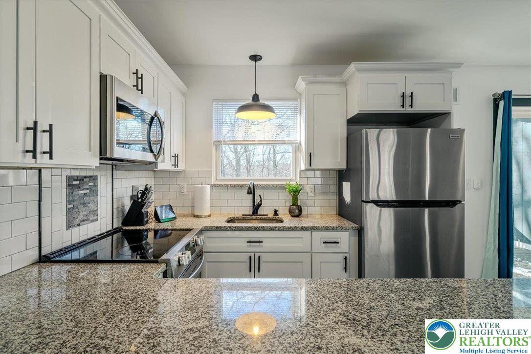 3260 Bluebird Drive Bushkill, PA 18324 - Photo 8 of 28 a kitchen with stainless steel appliances granite countertop a refrigerator a sink a stove a microwave and island