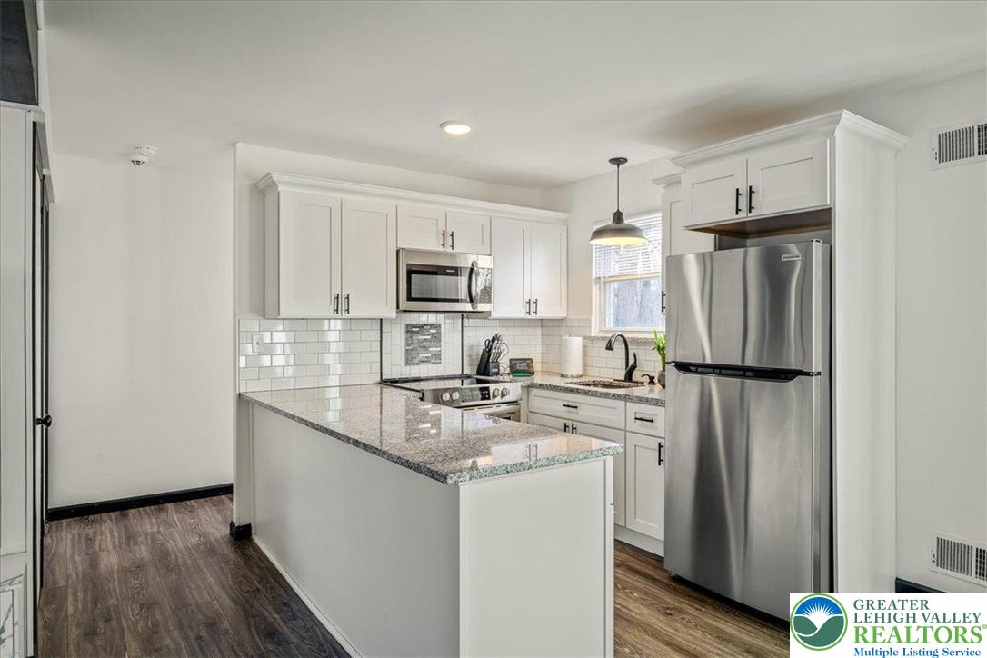 3260 Bluebird Drive Bushkill, PA 18324 - Photo 9 of 28 a kitchen with stainless steel appliances granite countertop a refrigerator a stove a sink and white cabinets with wooden floor