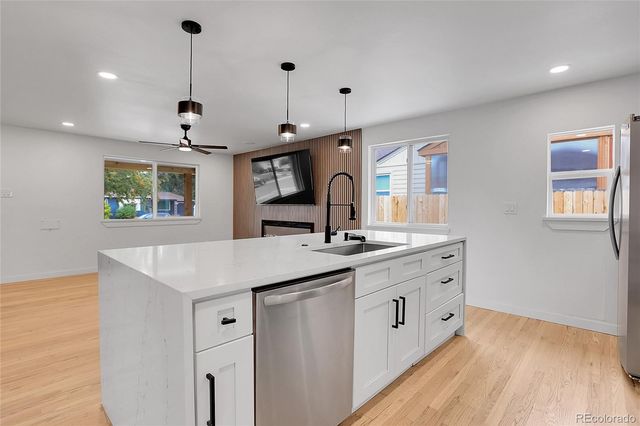 a kitchen with stainless steel appliances granite countertop a sink a stove and a wooden floors