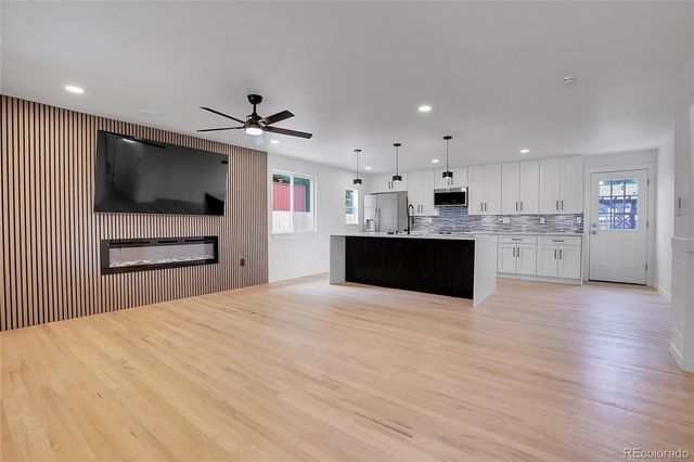 a large kitchen with stainless steel appliances kitchen island a fireplace and a flat screen tv