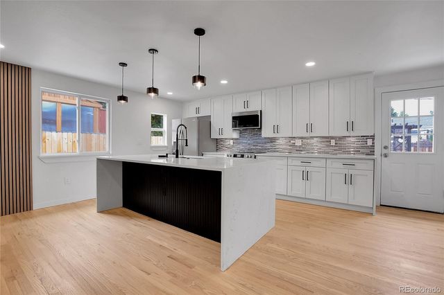 a kitchen with kitchen island granite countertop a sink appliances and cabinets